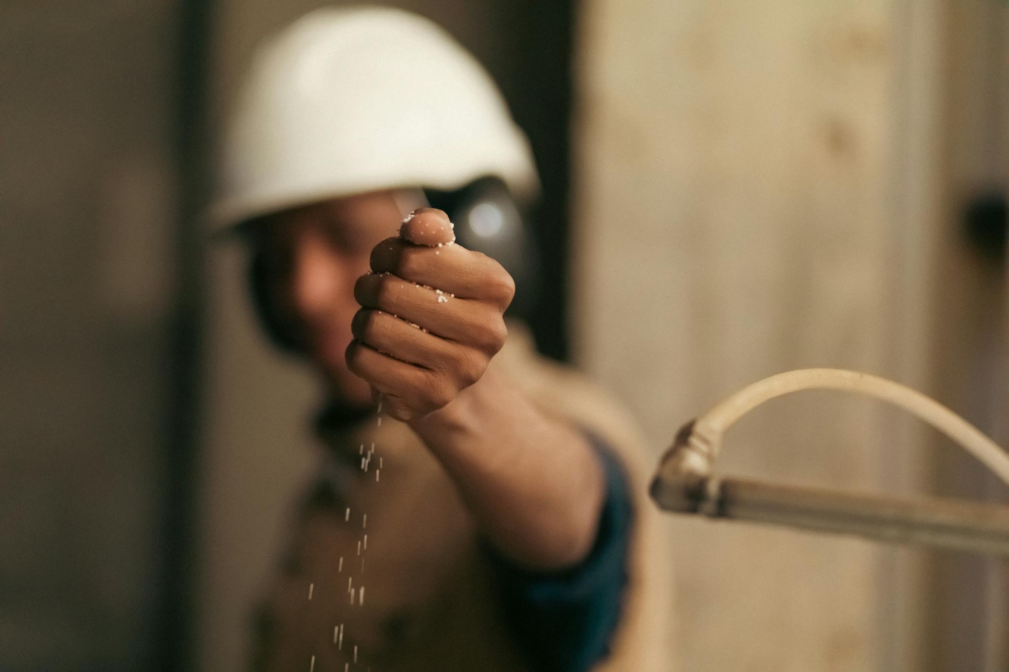 A worker in a hard hat holds granules, symbolizing the urea industry in Libya.